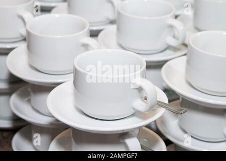 Reihen gestapelte Tassen und Untertassen betriebsbereit. Stockfoto