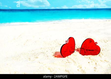Rote Herzen am weißen gelben Strand. Liebeskonzept für Valentinstag oder Sommerurlaub in tropischen Ferien. Stockfoto
