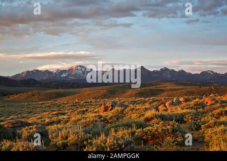 WY03960-00...WYOMING - Die untergehende Sonne, die warmes Licht über offenen Präriegebieten wirft, und der Wind River Reichen vom Hochland über dem Big Sandy Stockfoto