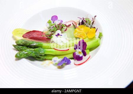 Eine farbenprächtige Schale mit frischen Spargel mit Gurke, Salat und essbare Blumen serviert. Stockfoto
