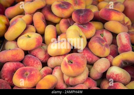 Saturn Pfirsichhintergrund. Pfanne tao Pfirsich, Prunus persica, flacher Pfirsich, Donut/Donut Pfirsichfrüchte auf dem Markt. Stockfoto