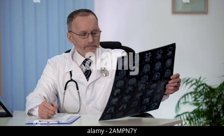 Neurologe untersuchen sorgfältig die Gehirn-MRT, die durch Ergebnisse gestört wird, und machen Notizen Stockfoto