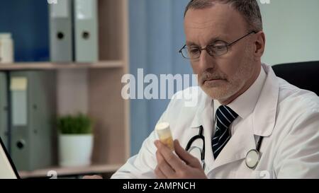 Zweifelhafter Arzt mit Blick auf Pillen, gefälschte Medikamente schlechter Qualität, Placebo Stockfoto