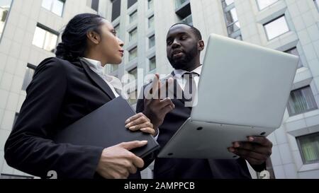 Afro-amerikanischer Geschäftsmann, der Assistent anführt und an einem Projekt arbeitet Stockfoto