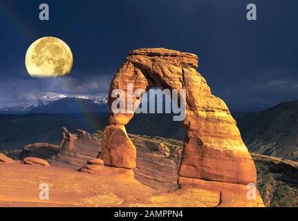 Ein Vollmond ragt über Den Delicate Arch im Arches National Park, Utah, auf. Stockfoto