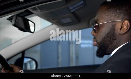Seriöser afroamerikanischer Mann, der Auto fährt und aufmerksam auf die Straße blickt Stockfoto