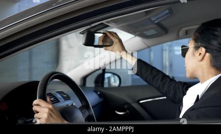 Geschäftsfrau, die im Rückspiegel, im Auto, im Verkehrsrecht schaut Stockfoto