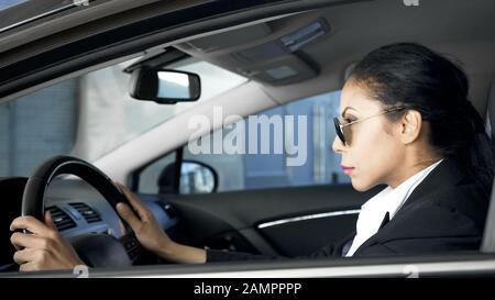 Selbstbewusste Frau im Business-Anzug sitzt im Auto nationale Sicherheitsmitarbeiterin im Dienst Stockfoto