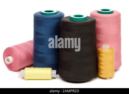Gruppe von Spulen aus rosa gelbblau und schwarz synthetischen oder Baumwollfäden auf weißem Hintergrund, die für das Weben in der Textilherstellung verwendet werden Stockfoto