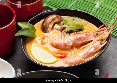 Tom Yum traditionelle thailändische Suppe mit Meeresfrüchten, Pilzen, Kokosmilch und heißen Gewürzen. Mit grünem Tee Stockfoto