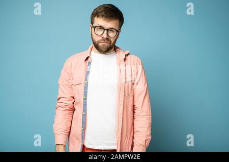 Gutaussehender, ruhiger, bärtiger Mann mit Brille verengte die Augen und schaut verdächtig auf die Kamera. Stockfoto