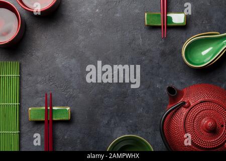 Grüner Tee in Schüsseln und Teekanne und Sushi-Essstäbchen auf Steintisch. Draufsicht mit Kopierbereich Stockfoto