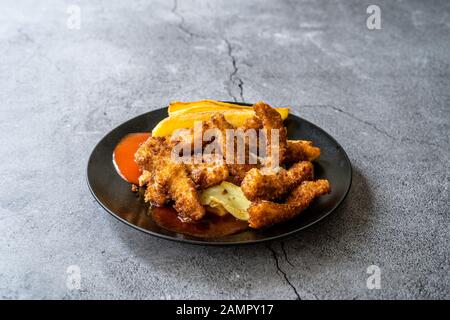 Fisch und Pommes Aus Paniertem und Gebratenen Seabass in schwarzem Teller. Fast Food. Stockfoto