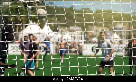 Sportliche Männer, die im Stadion Fußball spielen, sehen durch das Netz, gesunden Lebensstil Stockfoto