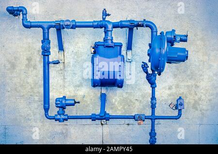 Seitenansicht der blauen nordamerikanischen Erdgasleitungen und des Versorgungsmeters, die an der alten stuckierten Gebäudewand montiert sind Stockfoto