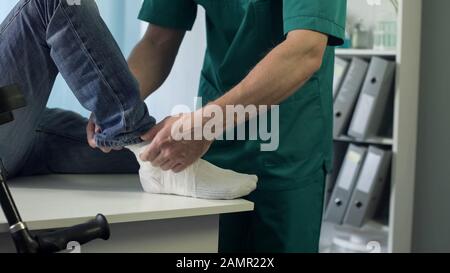 Physiotherapeut, der Gips auf Patienten mit gebrochenem Bein und Traumatherapie legt Stockfoto