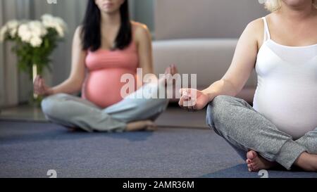 Zwei Frauen, die Yoga-Übungen für Schwangere machen, um sich zu Hause zu entspannen und zu beruhigen Stockfoto