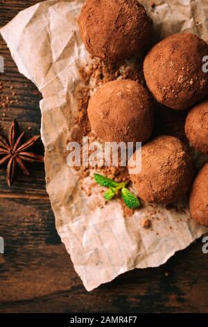 Hausgemachte dunkle Schokoladentrüffel auf Pergamentpapier, Draufsicht. Süße vegane Schokoladentrüffel Stockfoto