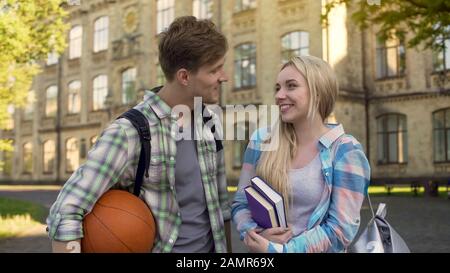 Gutaussehender Kerl, der mit hübscher Studentin flirtet und Mädchen vorschlägt, ins Kino zu gehen Stockfoto