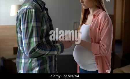Verärgert schwangeres Paar, das die Hände zusammenhält und finanzielle Schwierigkeiten hat Stockfoto