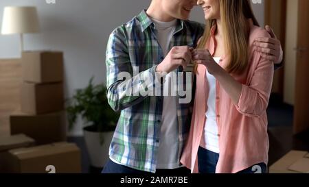 Junge Familie hält Schlüssel aus der neuen Wohnung an der Kamera und zieht zusammen Stockfoto