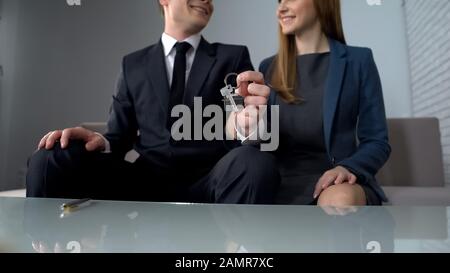Junges Paar, das Schlüssel aus dem neuen Haus hält, glückliche Kunden der Immobilienagentur Stockfoto