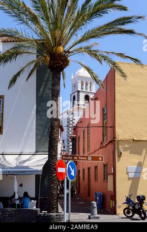 Der Kirchturm der Kirche Santa Ana wurde unter den kleinen Gebäuden der nahe gelegenen Straßen in Garachico gesehen. April 2019. Garachico, Santa Cruz De Tene Stockfoto