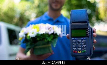 Blumen Lieferer mit Blumenstrauß und Zahlungsterminal, Kundenbetreuung Stockfoto