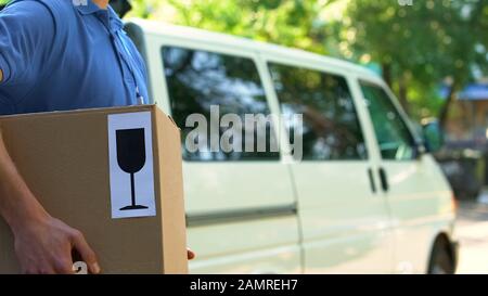 Der Lieferer, der das Paket hält, war zerbrechlich, vorsichtig in Bezug auf Arbeit und Versand Stockfoto