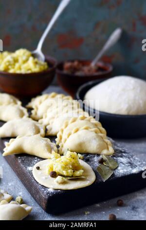 Knödel mit Kartoffeln mit Kräutern auf einem blauen Hintergrund. Wareniki, vareniki, Pierogi, pyrohy-Knödel mit Füllung. Stockfoto