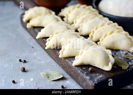 Knödel mit Kartoffeln mit Kräutern auf einem blauen Hintergrund. Wareniki, vareniki, Pierogi, pyrohy-Knödel mit Füllung. Stockfoto