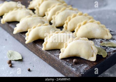 Knödel mit Kartoffeln mit Kräutern auf einem blauen Hintergrund. Wareniki, vareniki, Pierogi, pyrohy-Knödel mit Füllung. Stockfoto