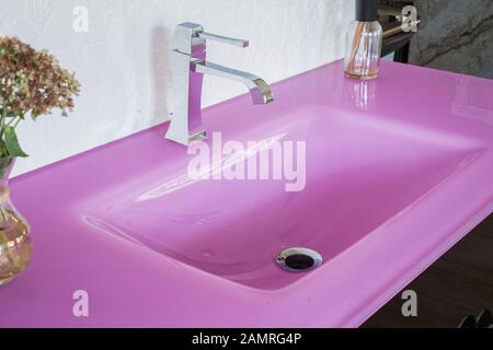 Nahaufnahme einer rosa Stein von einer glänzenden Waschbecken, in einem eleganten Interieur, mit Blumen. Blick von oben auf die Waschbecken im Badezimmer Stockfoto