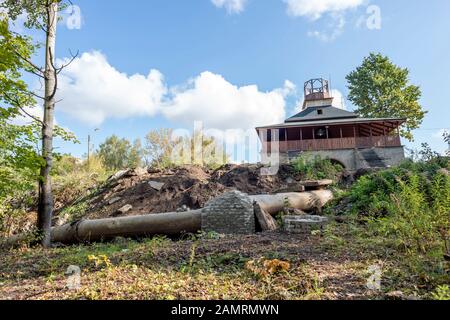 Ein in Bau befindlicher Sakralbau mit Abwasserkanal zum Waldgebiet. Konzept: Die Kirche leitet Abwasser in den Tempel der Natur ein. Stockfoto