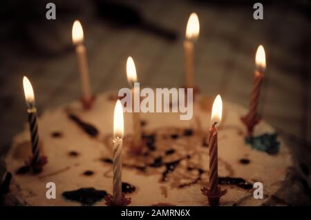 Nahaufnahme eines Geburtstags- oder Jubiläumstakens, der mit sieben Kerzen in vielen Farben verziert ist, die angezündet werden sollen Stockfoto