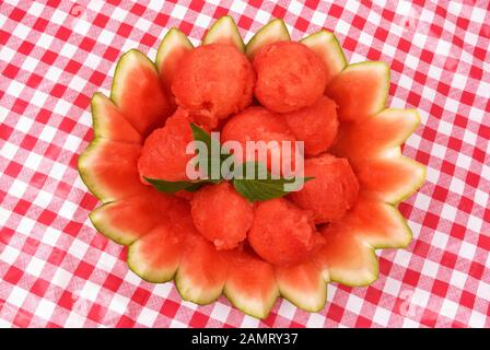 Wassermelon-Obstsalat in einer dekorativen Wassermelonenrindenschale. Für eine Pfändung werden süße Stevia-grüne Blätter hinzugefügt. Stockfoto