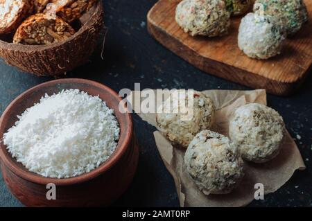 Hausgemachte vegane Schokoladentrüffel Pralinen und Nüsse mischen Zutaten auf dunklem Hintergrund, Draufsicht, Rand. Gesunde Süßigkeiten. Energie vegane Bälle mit dat Stockfoto