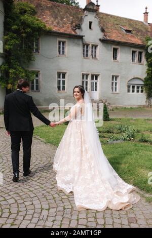 Jungvermählten sind zu Fuß in den Park in der Nähe der großen Burg. Schöne Braut mit stattlichen Bräutigam Stockfoto
