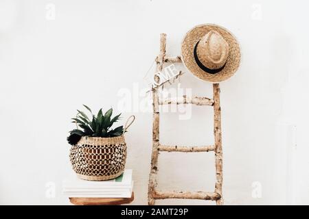 Pflanzen Sie in einem macrame Halter auf einem Holzhocker neben einer Leiter Stockfoto