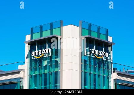 Amazon-Logo mit seinem unverkennbaren orangefarbenen Lächeln auf der Glasfassade des Firmencampus im Silicon Valley - Palo Alto, Kalifornien, USA - Oktober 2019 Stockfoto