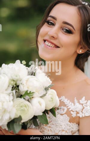 Close up Portrait von wunderschöne Braut mit Blumenstrauß. Glückliche Frau lächeln Stockfoto