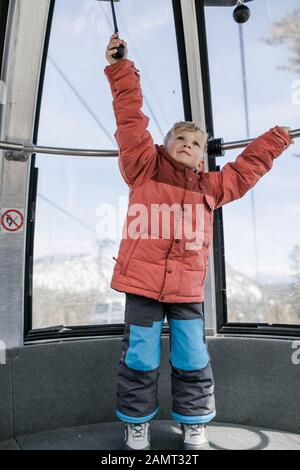 Der Junge, der in einer Seilbahn steht, die auf einem Geländer hält, Mammoth Lakes, Kalifornien, USA Stockfoto