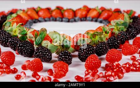 Liebessymbol Herz aus bunten Beeren auf weißem Hintergrund. Stockfoto