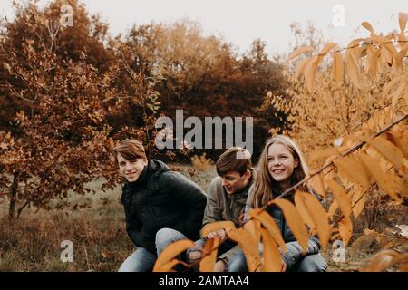 Drei Kinder sitzen zusammen in der ländlichen Landschaft, Niederlande Stockfoto