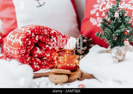 Weihnachtskekse, Kerze und kleine Weihnachtsbaumanordnung neben Kissen und einem Teppich Stockfoto