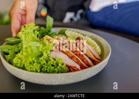 Hand serviert thailändische Würzig geschnittene gegrillte Schweinehals mit Gemüse an der Seite. Stockfoto