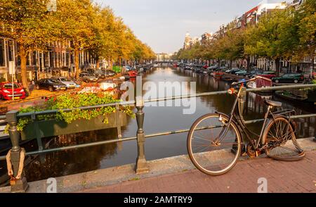 Ein gebrochenes und verlassenes Omafiets-Fahrrad wird auf einer Brücke über den Kaiser-Kanal im Amsterdamer Grachtengürtel Centrum an Geländer verschlossen gelassen. Stockfoto