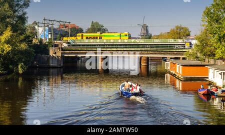 Amsterdam, Niederlande - 2. Oktober 2011: Eine Familie nimmt ein kleines Sportboot entlang des Lozingskanaals und unter der Amsterdam-Arnhem-Bahn in Th Stockfoto