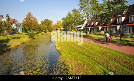 Niederlande - 29. September 2011: Ein Radfahrer fährt am modernen Reihenhaus neben einem Entwässerungskanal in der geplanten neuen Stadt Houten vorbei. Stockfoto