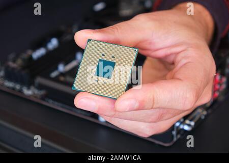 Computerchip (CPU), der von einem Mann mit den Fingern gehalten wird - Nahaufnahme des Pin-Rasters. Stockfoto